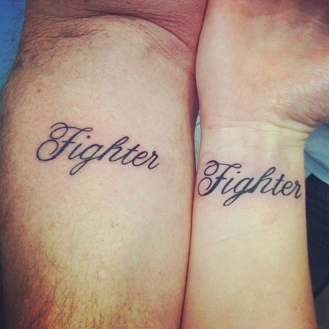 Father and daughter showcasing forearm tattoos of the word &quot;Fighter,&quot; a simple yet powerful word symbolizing strength and shared resilience, inspired by a song.