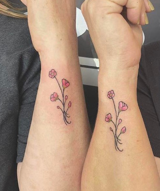 Delicate pink floral tattoos, representing blossoming friendship and feminine bonds