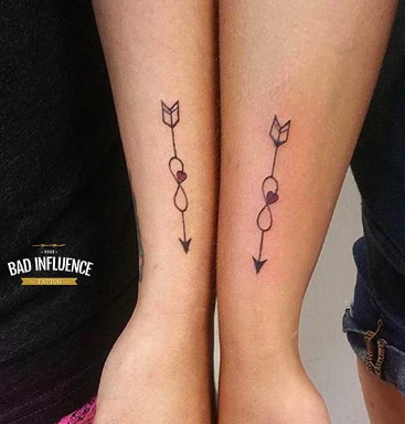 Infinity symbol intertwined with an arrow tattoo, representing eternal friendship and forward momentum