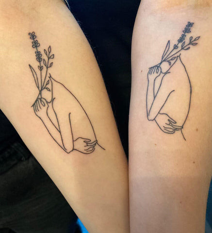 Matching floral tattoos on twin sisters, representing feminine energy and growth.