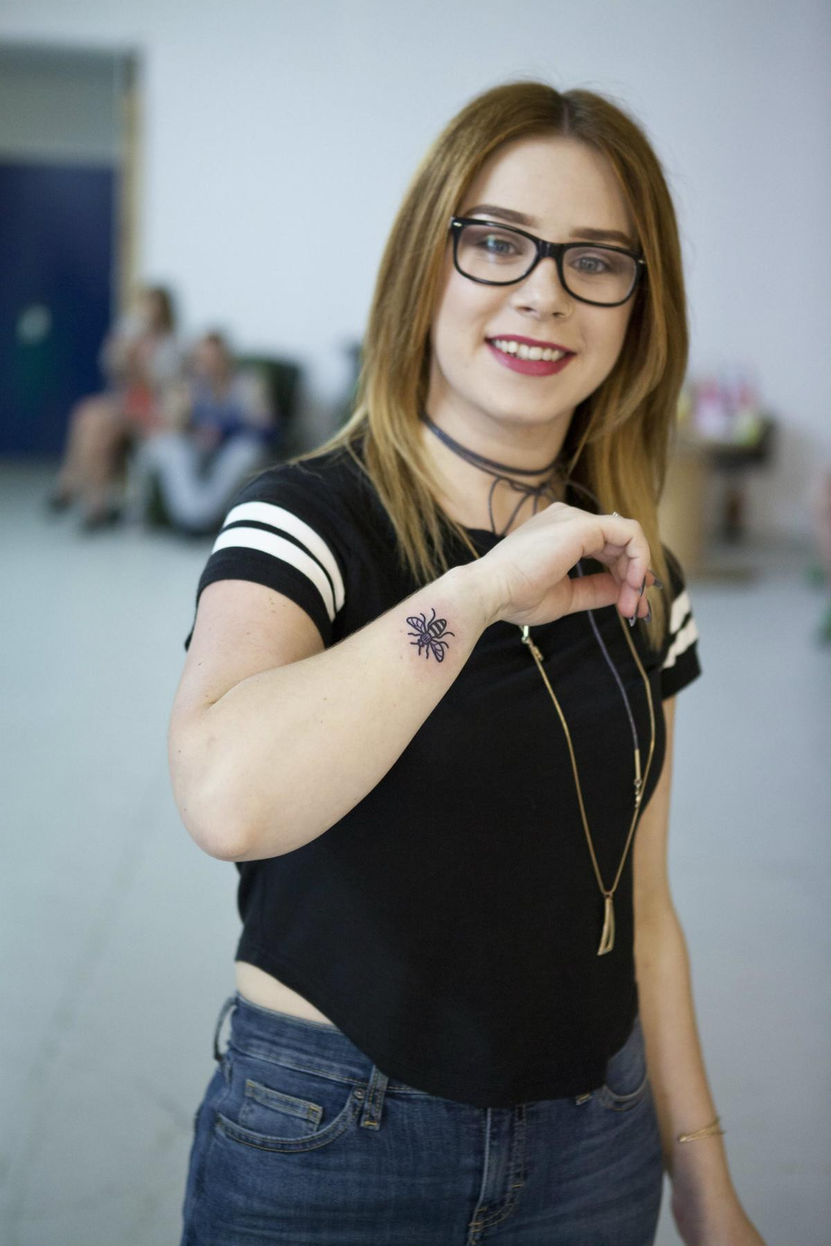 Man getting a bee tattoo on his arm, demonstrating the enduring popularity of bee tattoos and their connection to Manchester.