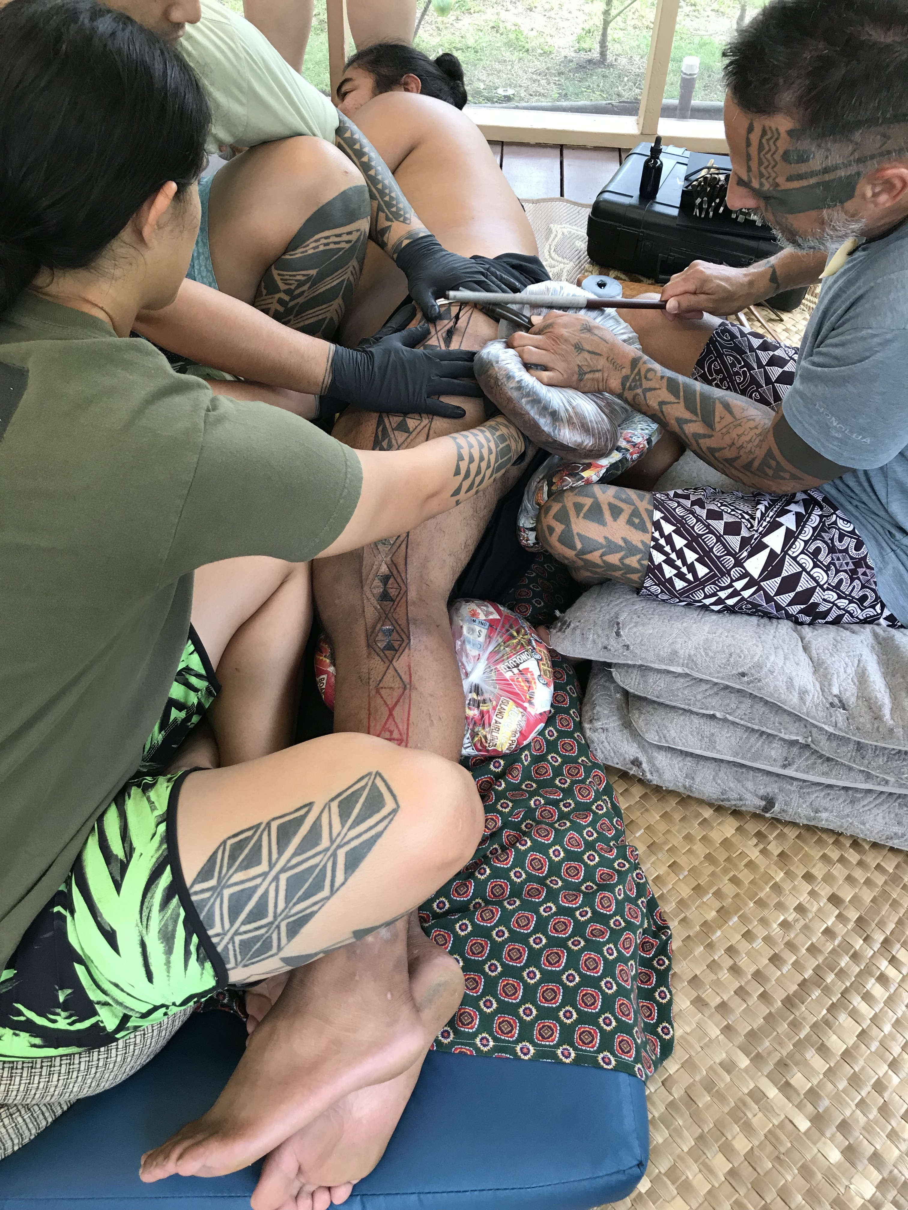 Kiha Rodrigues undergoing the traditional Hawaiian tattooing process of kākau, showcasing the hand-tapping method