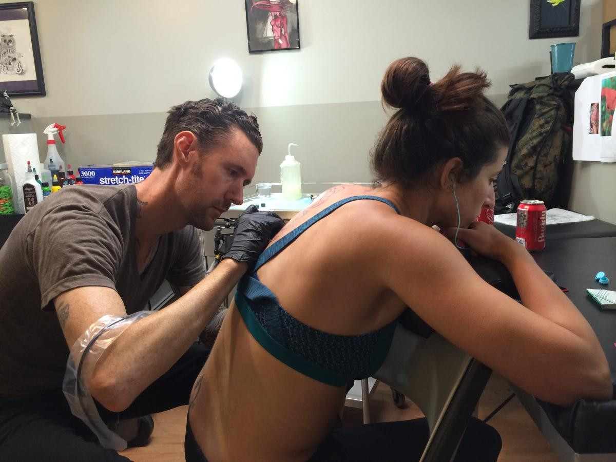 Tattoo artist Kevin at Bethesda Tattoo working on a large tattoo piece, three hours into the session, showcasing black shading work in progress.
