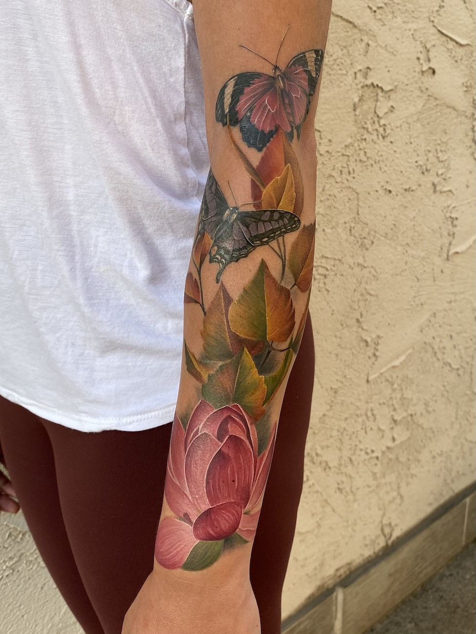 Upper arm tattoo of a bouquet of wildflowers with soft watercolor effect, embodying a modern feminine tattoo trend.