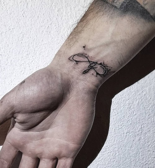 Infinity symbol intertwined with &quot;family&quot; script tattoo on a man's wrist, representing eternal family love.