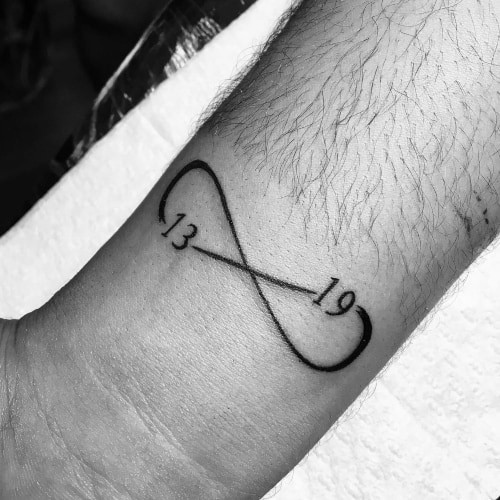 Infinity tattoo with names incorporated on the arm, symbolizing everlasting love in men tattoo ideas.