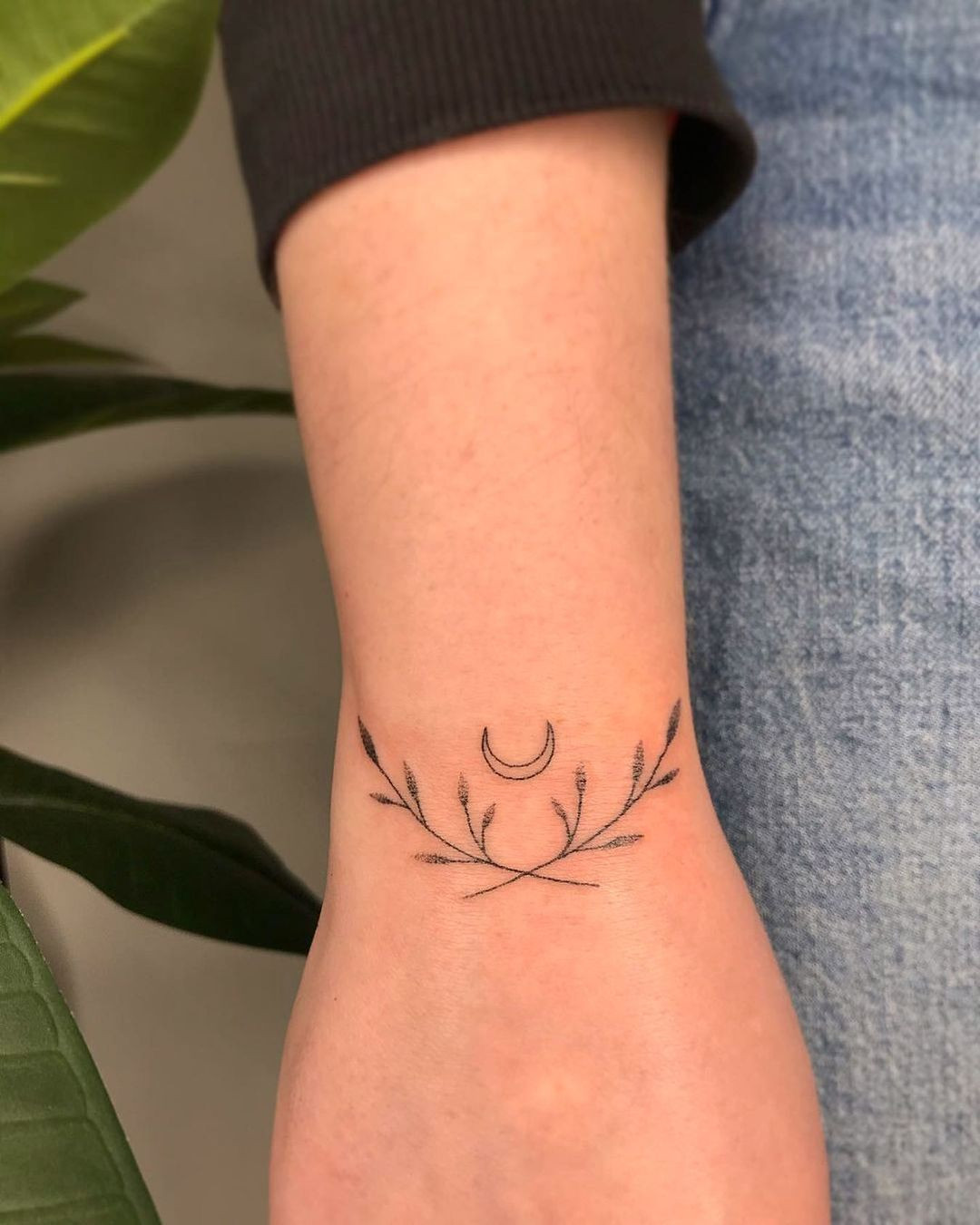 Moon and leaves bracelet tattoo on wrist, symmetrical and nature-inspired