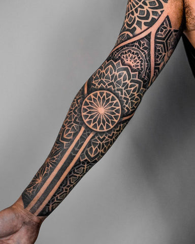 Intricate dotwork tattoo on the back of a man's outer forearm, showcasing fine lines and detailed shading.