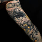 Intricate black and grey eye tattoo on an arm, showcasing detailed linework and shading, symbolizing watchfulness and inner vision.