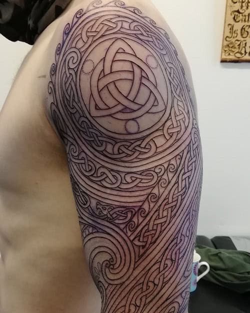 Irish tribal tattoo on a man's arm, showcasing intricate Celtic knotwork patterns.