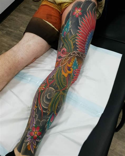 Vibrant Japanese leg sleeve tattoo with dragon and floral motifs