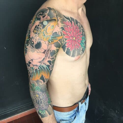 Japanese sleeve tattoo featuring dragons, waves, and floral elements