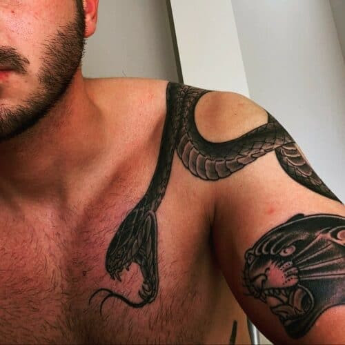 Detailed Japanese snake tattoo coiled around an arm with floral accents