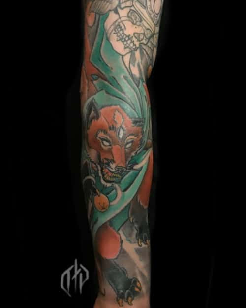 A Japanese wolf tattoo on a man's sleeve, showcasing vibrant colors, traditional Japanese tattoo art style, and symbolism of protection and good luck for travelers.
