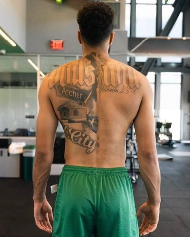 Jayson Tatum's back tattoo with &quot;God's Will&quot;, a crucifix, and his childhood home, symbolizing faith and roots.