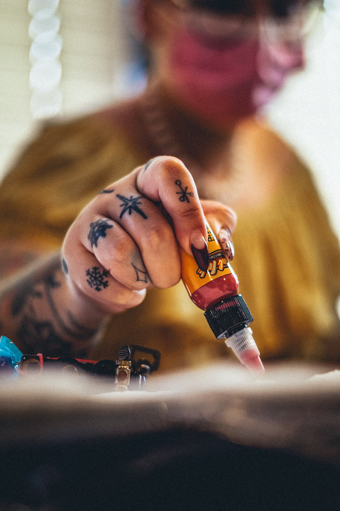 A person's arm with a tattoo showing signs of an allergic reaction, characterized by redness, swelling, and small bumps around the colored ink.