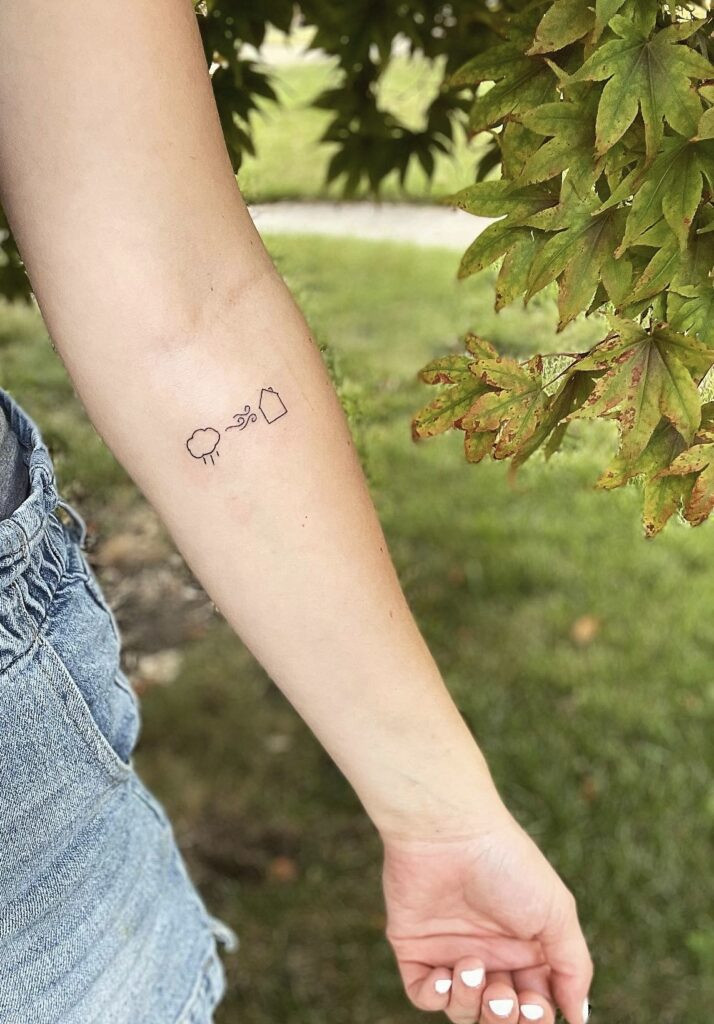 Small tattoo of lines representing &quot;Rain came, wind blew, but my house was built on You&quot; lyrics on Julia C.'s wrist, symbolizing faith and resilience.