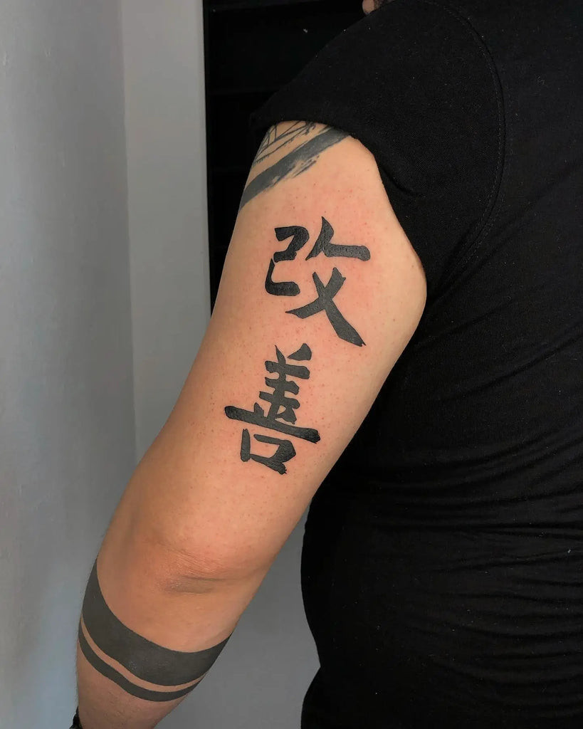 Minimalist black ink Kaizen Kanji tattoo on the wrist, symbolizing continuous improvement