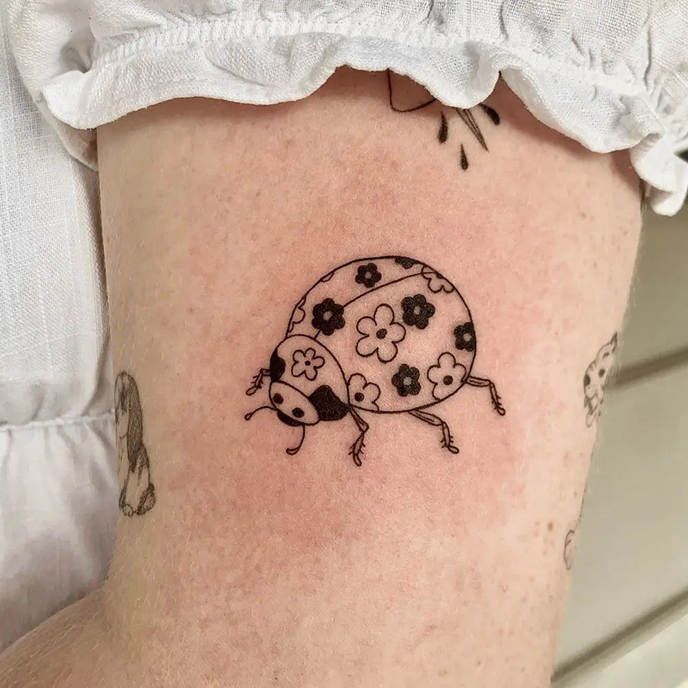 A black and grey ladybug tattoo, emphasizing form and subtle shading, created by Bigbev_ink