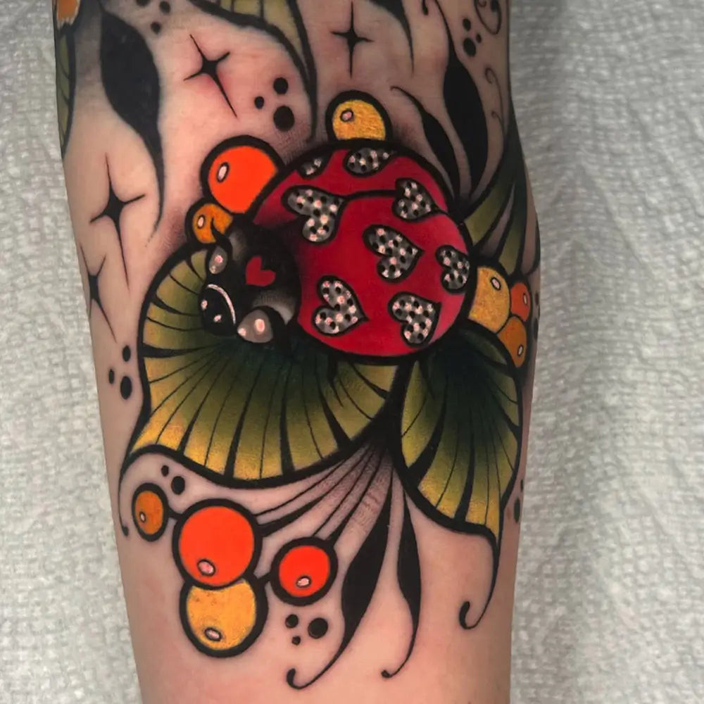 A detailed ladybug tattoo with intricate patterns and embellishments, created by Exhalenoelletattoos