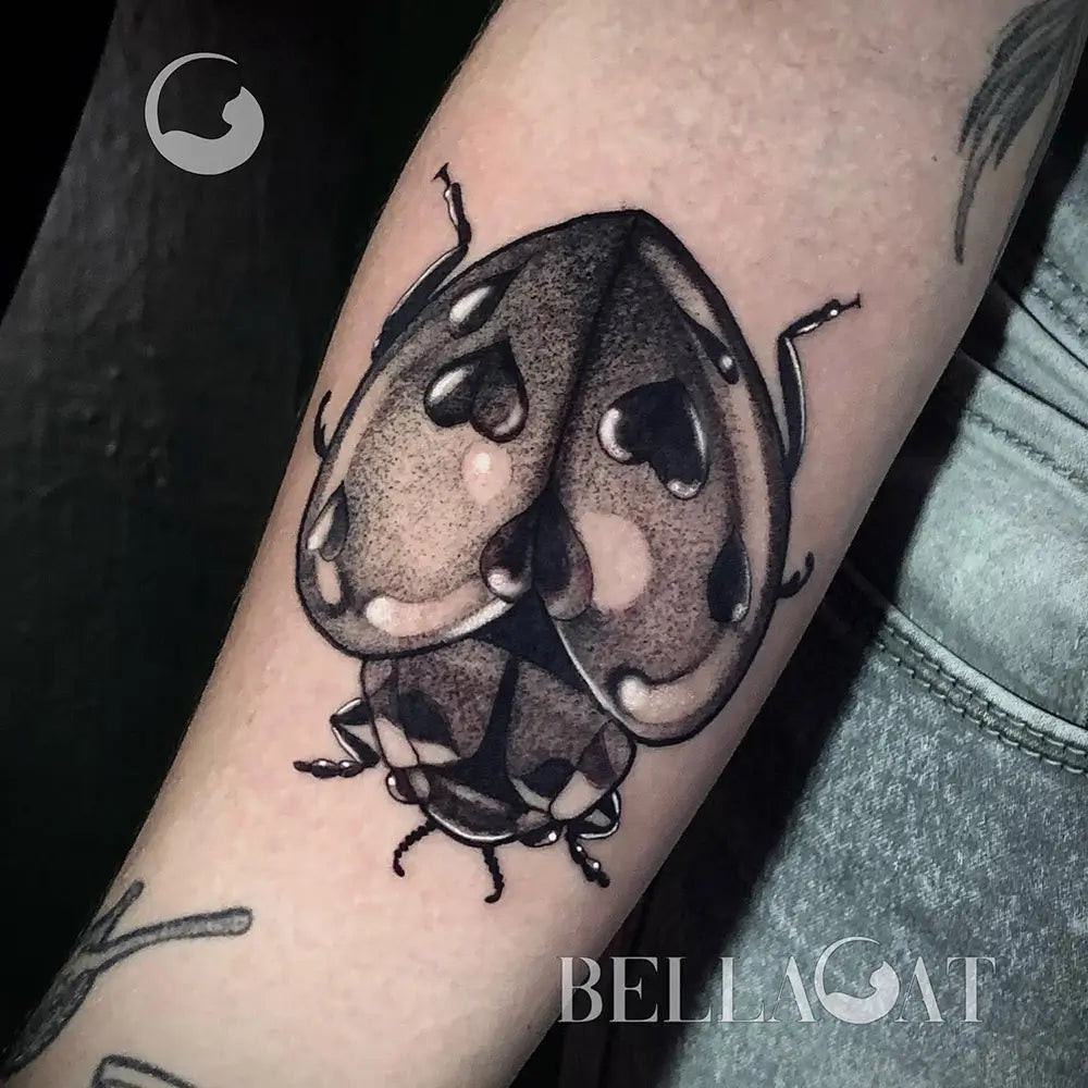 A ladybug tattoo incorporating personal symbols, making it uniquely meaningful, created by Bellacat.tattoo