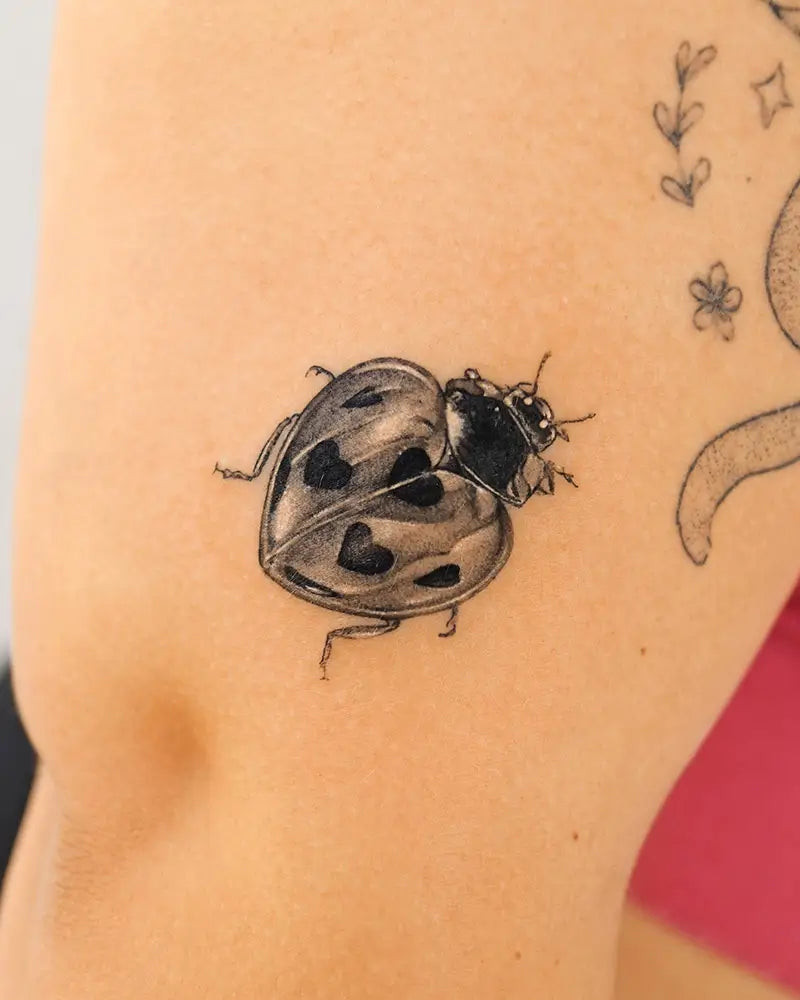 A cute and playful ladybug tattoo with a smiley face, expressing joy and playfulness, created by Tattooist_yun