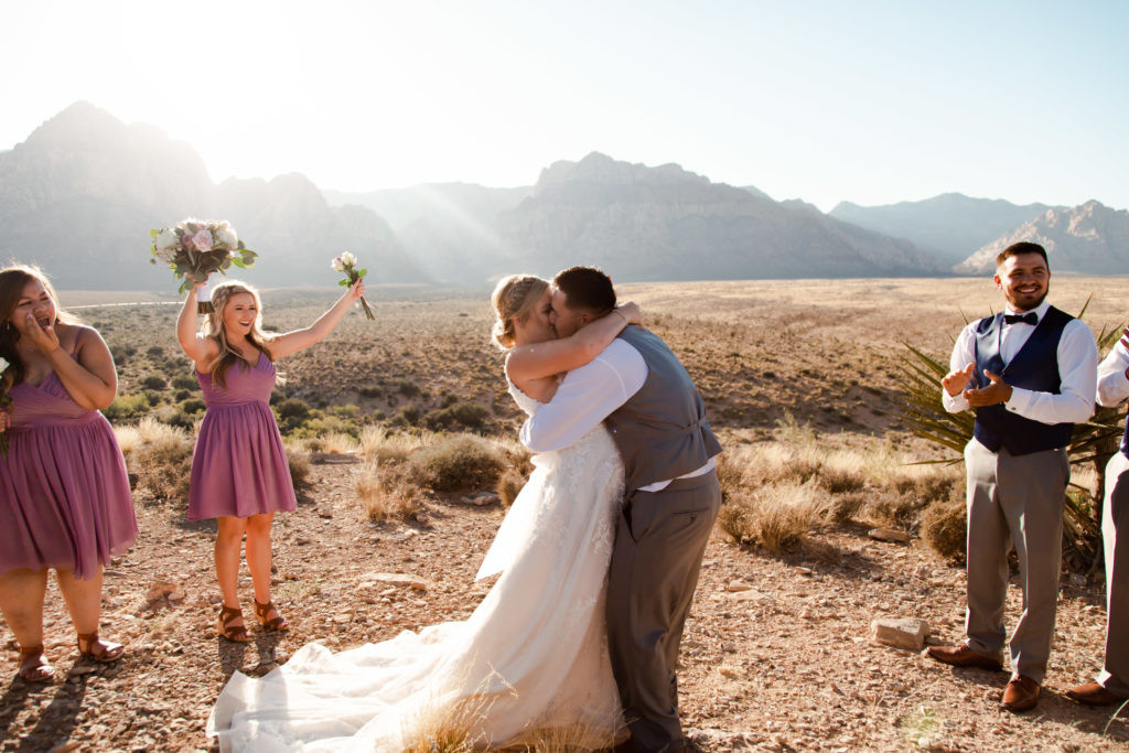 Eloping couple holding hands and walking in the desert landscape.