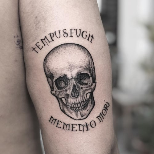 Two latin tattoos on men, one on the forearm with a Latin quote and another on the arm with a minimalist Latin phrase.