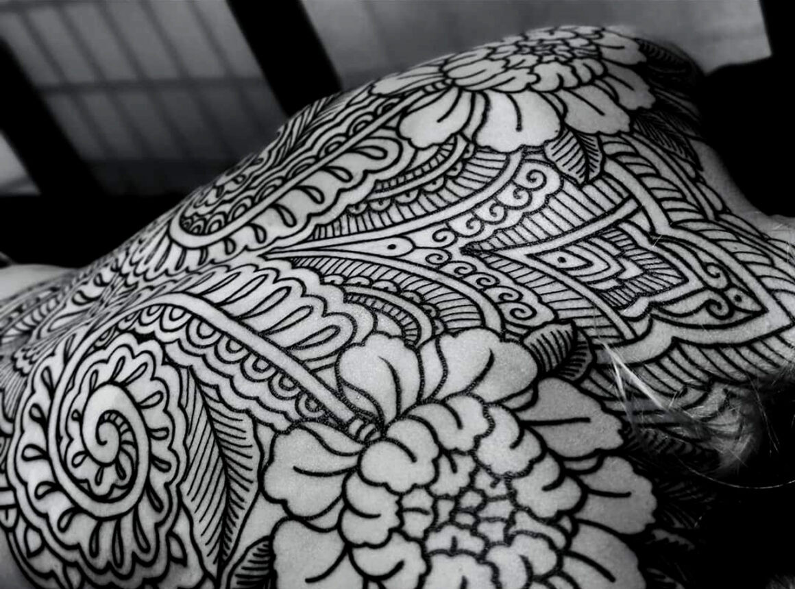Ornamental tattoo on back featuring geometric patterns and clean black lines by Lenn Black Lotus.