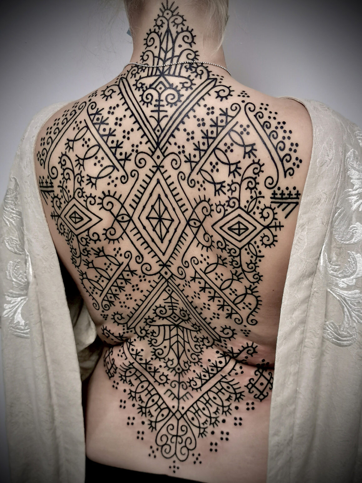 Detailed black lotus tattoo design on leg, reflecting folk art and ornamental inspiration.