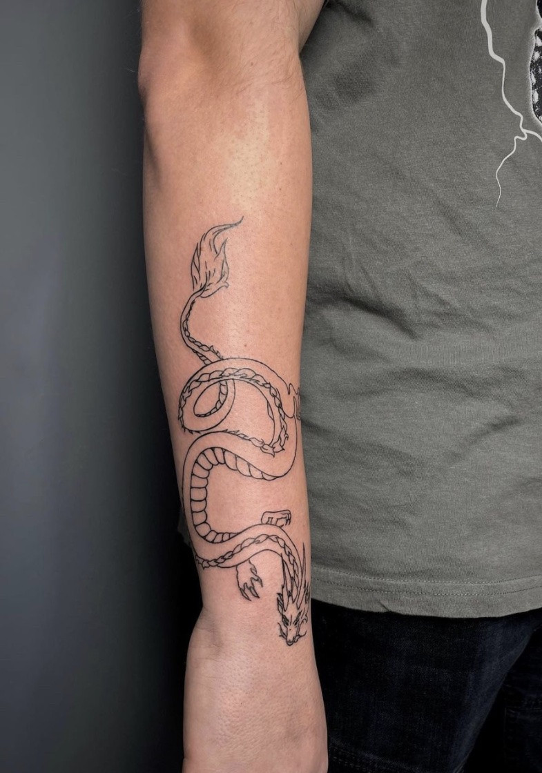 Clean linework dragon outline tattoo on arm