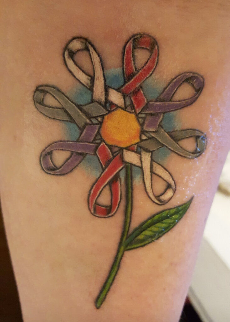 A flower tattoo crafted from gray ribbons, symbolizing brain tumor journey and strength.