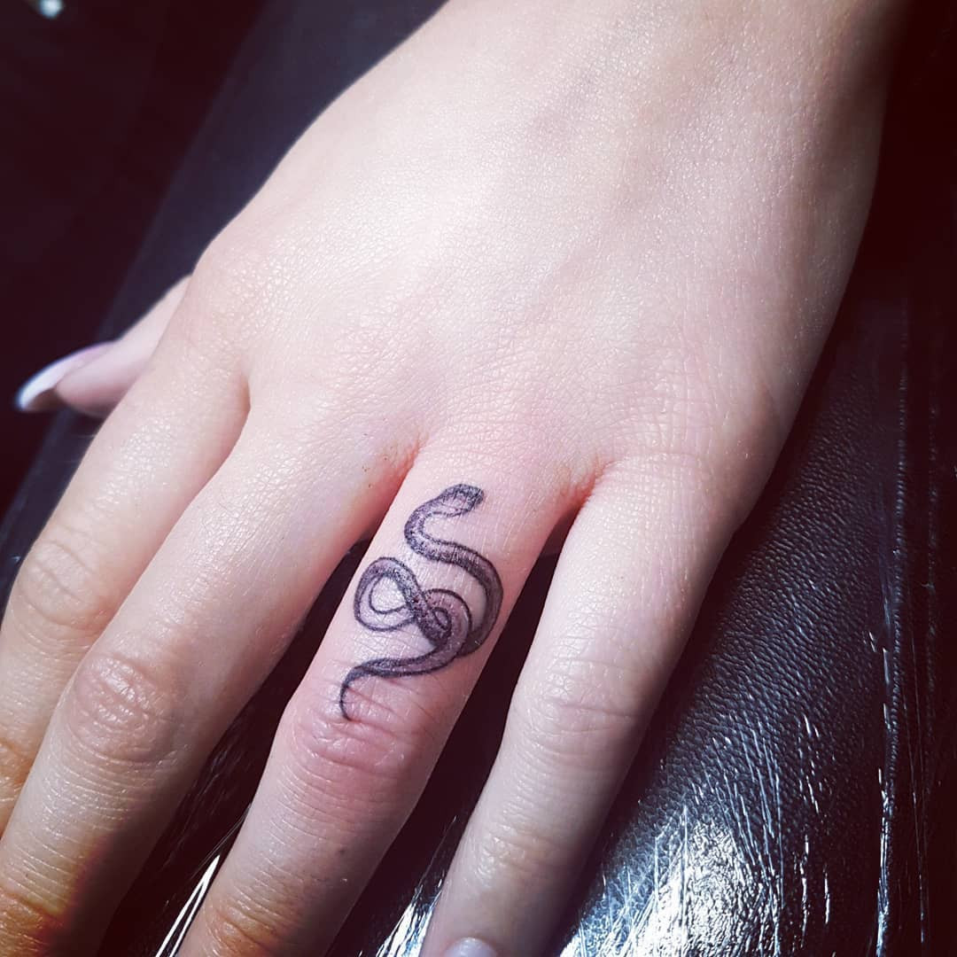 Snake finger tattoo flowing elegantly on the finger