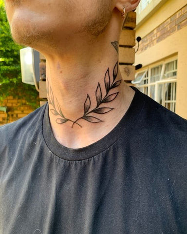 A man displaying a minimalist lower neck tattoo design