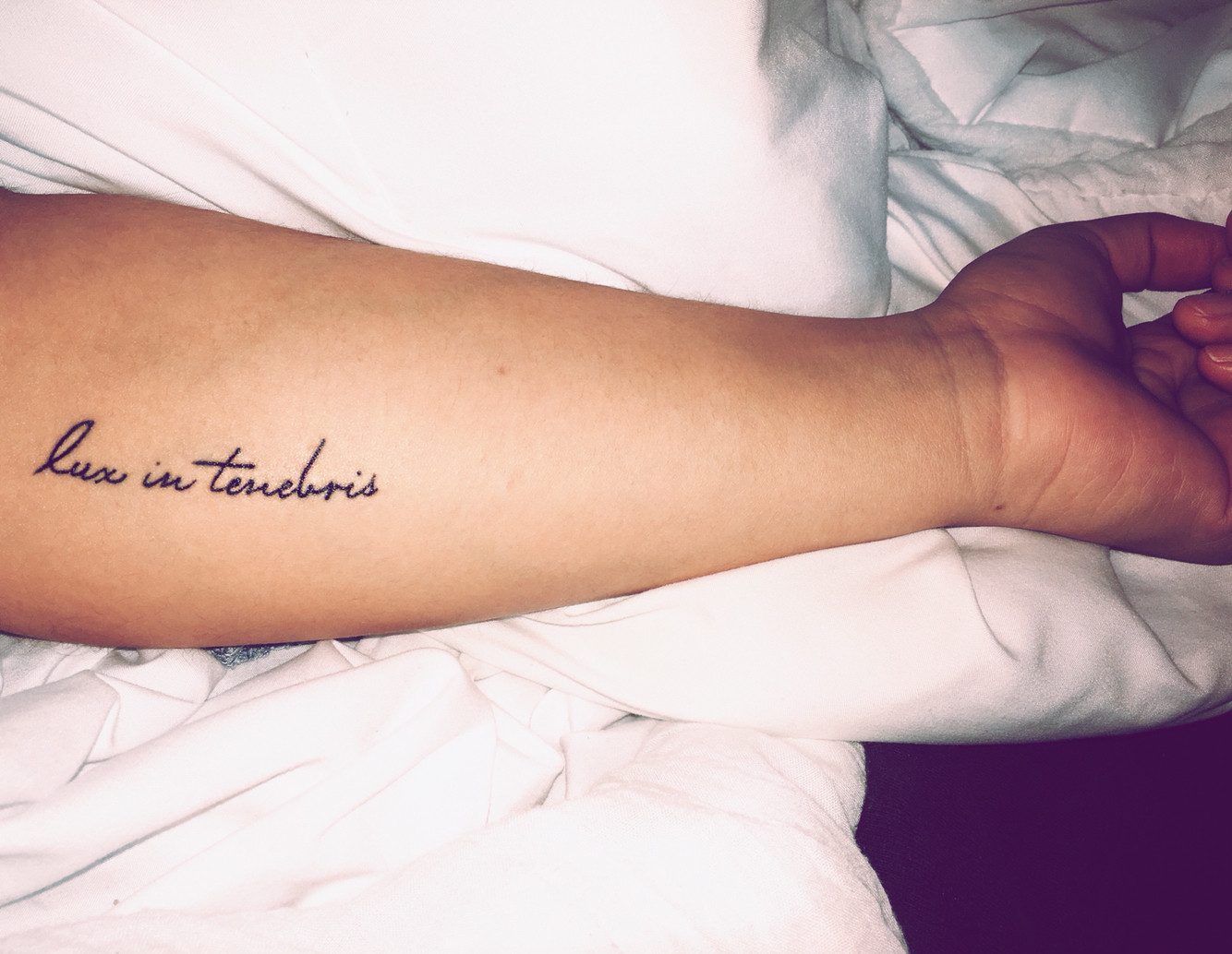 &quot;Lux in Tenebris&quot; word tattoo on ribs in elegant font, symbolizing hope in darkness