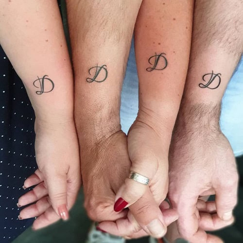 Matching minimalist family symbol tattoos on family members' wrists, a symbol of shared family bond.