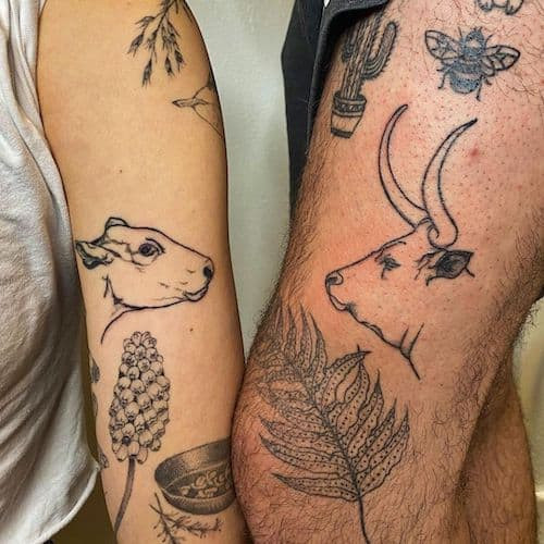 Two matching tattoos on men, one on the chest with stylized matching animal halves and another on the shoulder with geometric matching patterns.