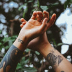 A person's arm with a detailed bird and floral tattoo, symbolizing freedom and remembrance.