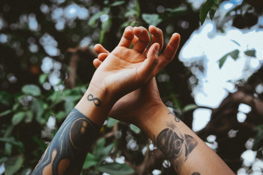 A person's arm with a detailed bird and floral tattoo, symbolizing freedom and remembrance.