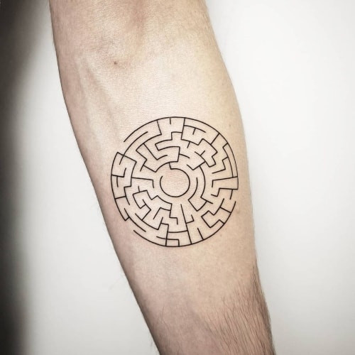 A maze tattoo with detailed pathways on a man's arm, symbolizing life's journey