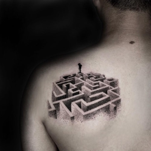 A minimalist maze outline tattoo on a man's wrist, subtle and symbolic of complexity