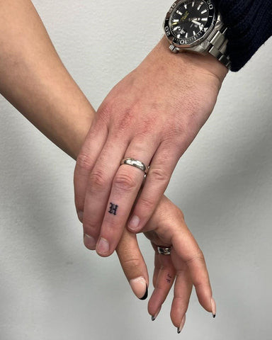 Ring finger tattoo of simple black line, alternative to wedding band, on man's hand