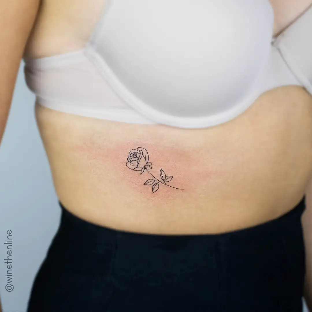 Minimalist rose outline tattoo on woman's ribs for subtle elegance