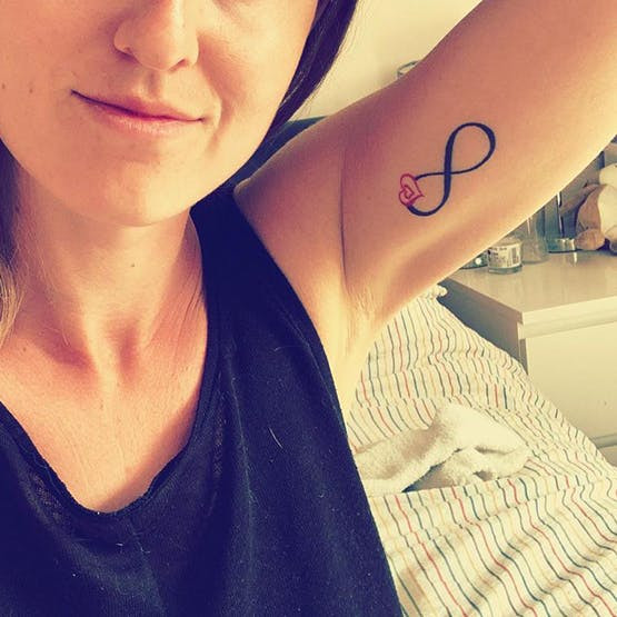 Infinity symbol miscarriage tattoo with baby feet on wrist.