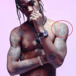 Monkey tattoo on Travis Scott's shoulder, depicting a monkey with headphones and a Celtic cross