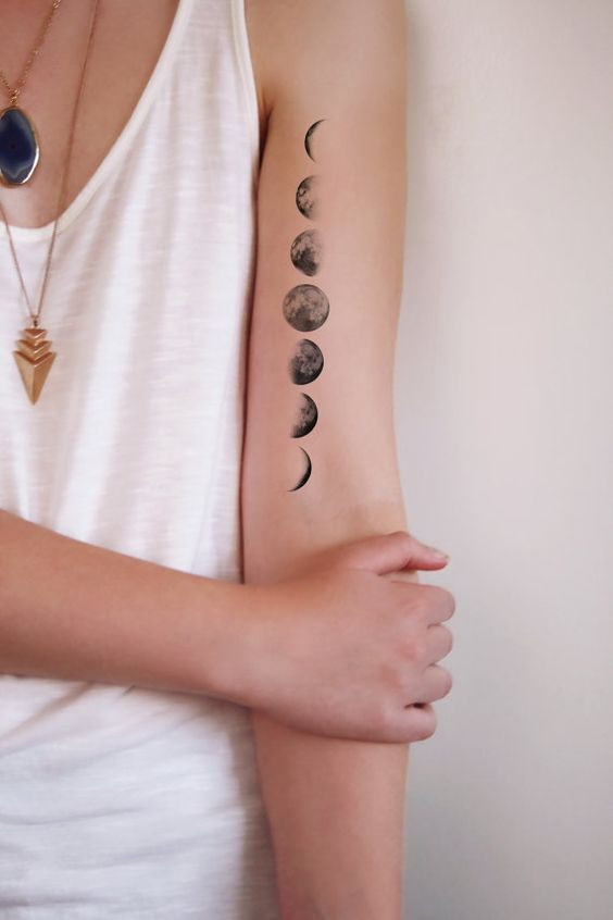 Crescent moon tattoo on wrist, minimalist black outline.