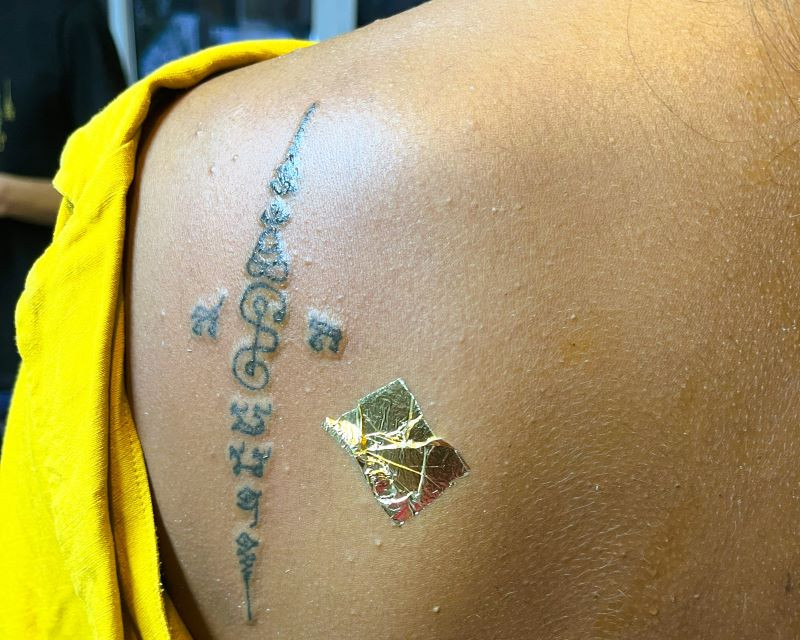 Close-up of a freshly completed Sak Yant tattoo, blessed with a gold leaf for enhanced spiritual power.