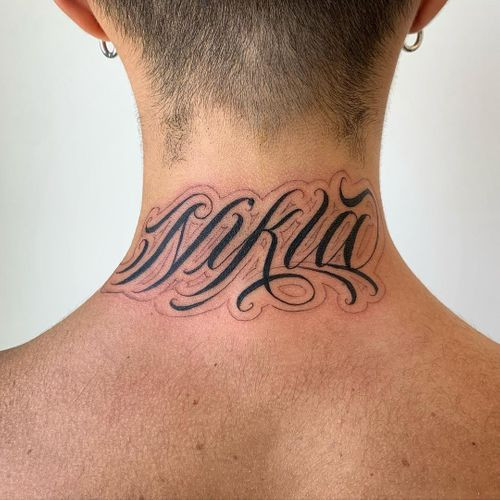 A name tattoo in a flowing script on a man's forearm, honoring a loved one