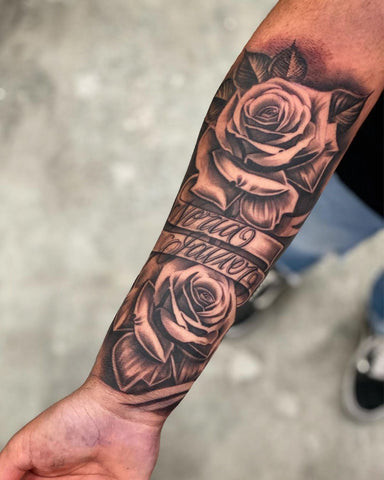 Forearm tattoo with a prominent name script intertwined with delicate roses, a heartfelt tribute to a loved one.