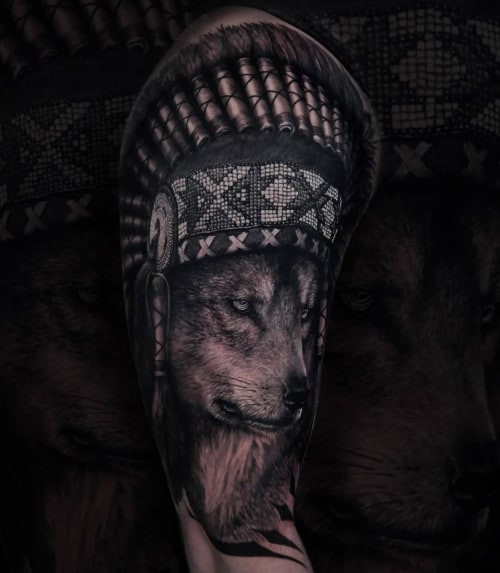 A Native American wolf tattoo on a man's thigh, incorporating indigenous art styles and symbolic elements to represent courage, spiritual connection, and respect for nature.
